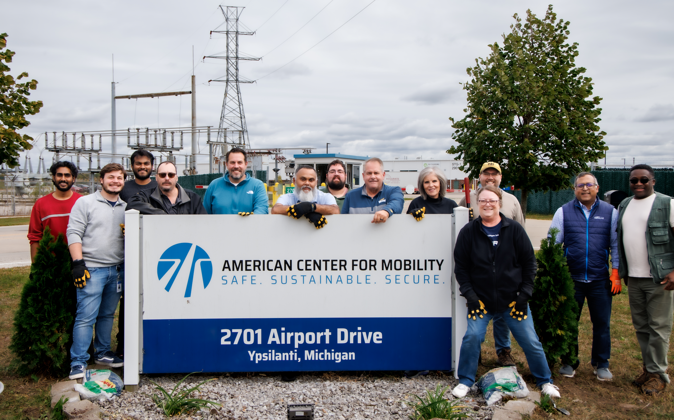 Team members from American Center for Mobility at the front entrance sign